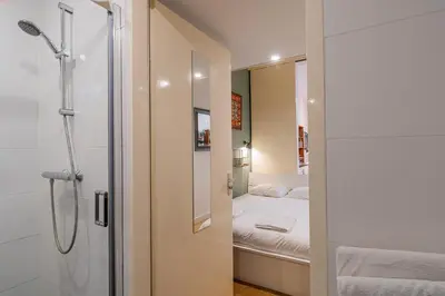 a small bathroom with a shower and a bed at Stylish Private Studio Close to City in Amsterdam