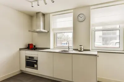 a kitchen with white cabinets and a clock on the wall at Luxury Family Residence Schinkeldijkje in Aalsmeer