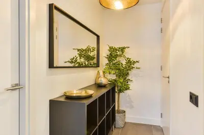 a mirror on a wall above a dresser in a hallway at Luxury Family Residence Schinkeldijkje in Aalsmeer