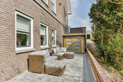 a patio with two couches and chairs next to a building at Luxury Family Residence Schinkeldijkje in Aalsmeer