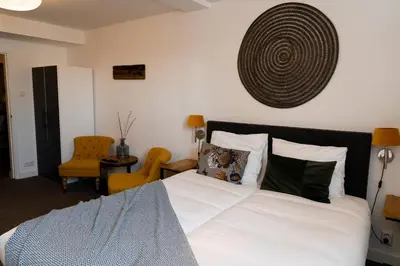 a bedroom with a bed with white sheets and pillows at Boutique Lodge Zandvoort in Zandvoort