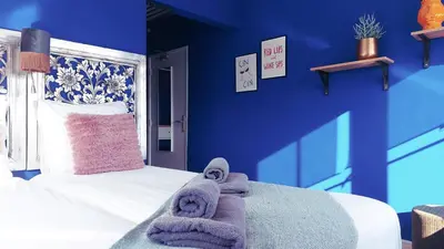 a bedroom with blue walls and a bed with towels on it at Boutique Lodge Zandvoort in Zandvoort