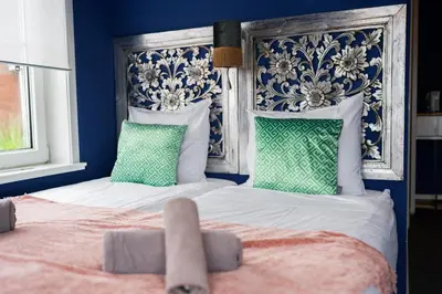 two beds in a bedroom with blue walls and green pillows at Boutique Lodge Zandvoort in Zandvoort