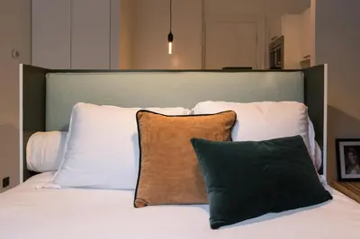 a bed with white pillows and a green headboard at Canal Suite City Centre in Amsterdam