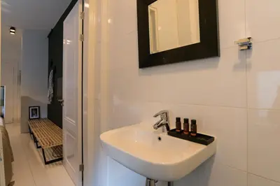 a white bathroom with a sink and a shower at Canal Suite City Centre in Amsterdam