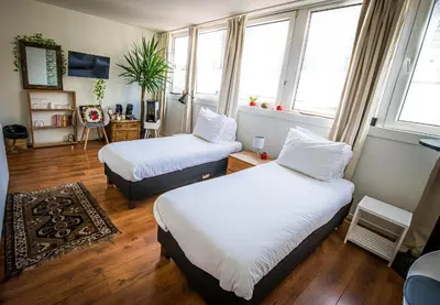 two beds in a room with two windows at City Break Amsterdam in Amsterdam