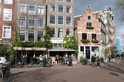 a group of people walking on a city street with buildings at City Heart Station Amsterdam in Amsterdam