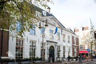 a white building with a flag in front of it at City Heart Station Amsterdam in Amsterdam