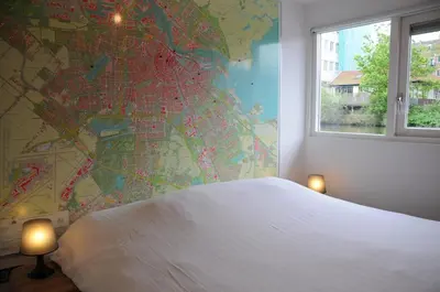 a bedroom with a large white bed and a map on the wall at Boathotel in Amsterdam
