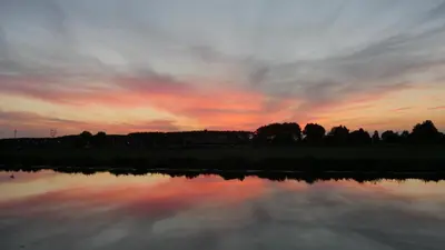 a sunset over a body of water with the sky at Groeten uit Hoogmade - rural cottage in Hoogmaden
