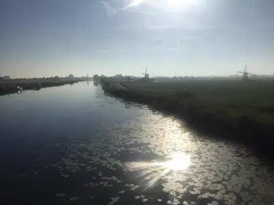 a river with the sun reflecting on the water at Groeten uit Hoogmade - rural cottage in Hoogmaden