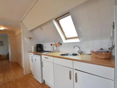 a kitchen with white cabinets and a sink and a window at Apartment in North Holland in Bergen aan Zee