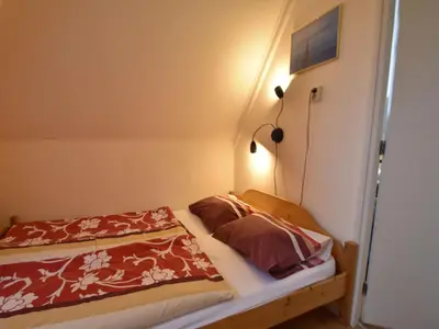 a small bedroom with a bed with a red blanket at Apartment in Bergen aan Zee near the Beach in Bergen aan Zee