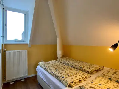 two beds in a room with yellow walls and a window at Apartment in Bergen aan Zee near the Beach in Bergen aan Zee