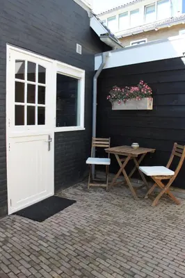 a patio with a white door and a table and chairs at Viale in Egmond aan Zee