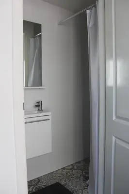 a white bathroom with a sink and a mirror at Viale in Egmond aan Zee