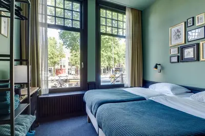 a bedroom with two beds and two windows at SeventyFive in Amsterdam