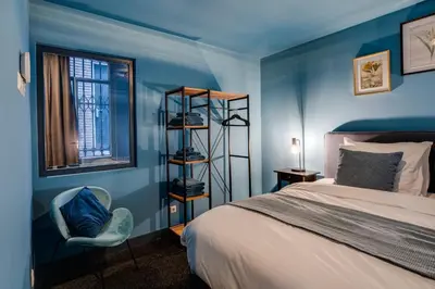a blue bedroom with a bed and a chair and a window at SeventyFive in Amsterdam