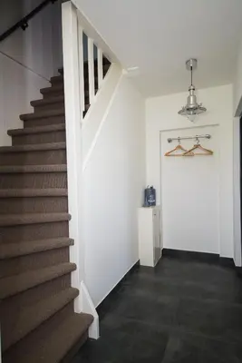 a hallway with stairs and a white wall at Gastenverblijf Eenigenburg in Eenigenburg