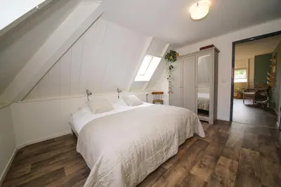 a bedroom with a large white bed in a attic at Gastenverblijf Eenigenburg in Eenigenburg