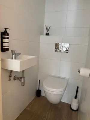 a white bathroom with a toilet and a sink at Koningshof XL in Alkmaar