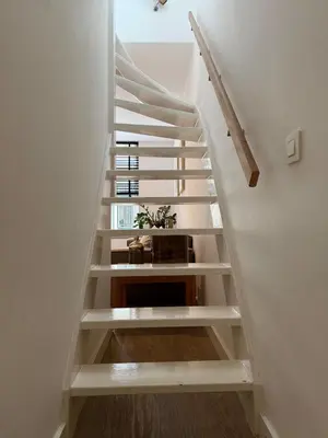 a staircase in a house with white walls and wooden floors at Koningshof XL in Alkmaar