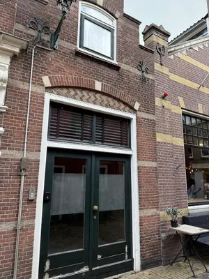 a brick building with a green door and a window at Koningshof XL in Alkmaar