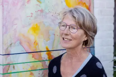 a woman wearing glasses standing in front of a painting at holiday cottage 'FLOW' in Bergen