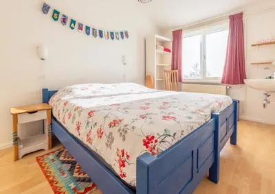 a bedroom with a blue bed with a floral bedspread at holiday cottage 'FLOW' in Bergen
