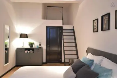 a bedroom with a bed and a spiral staircase at Romantic ground floor suite in Pijp near Sarphatipark in Amsterdam