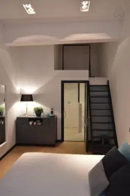 a bedroom with a bed and a staircase with a stair case at Romantic ground floor suite in Pijp near Sarphatipark in Amsterdam