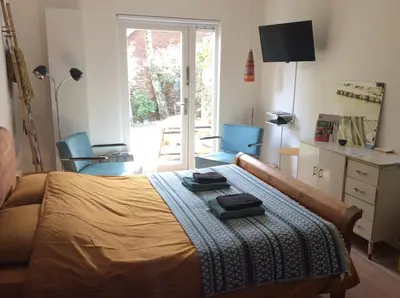 a bedroom with a bed with a blanket and two chairs at B&B PeperZzz in Bergen
