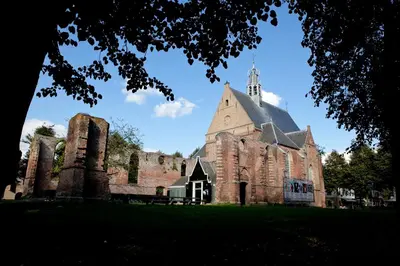 an old church with a tower on a grass field at B&B PeperZzz in Bergen