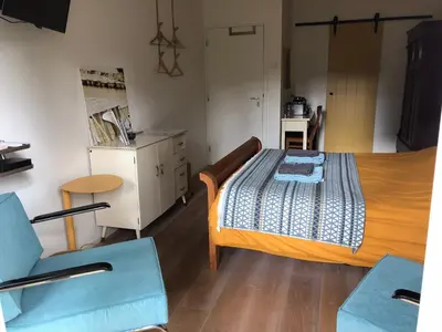 a bedroom with a bed and a table and a chair at B&B PeperZzz in Bergen