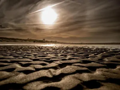a sandy beach with the sun in the sky at Holiday Home in Bergen near North Sea Beach in Bergen aan Zee