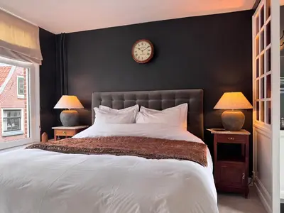 a bedroom with a large bed with a clock on the wall at The Lastage Inn - Bed & Breakfast in Amsterdam