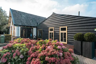 a black house with flowers in front of it at Veldzicht in Winkel