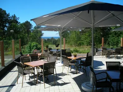 a patio with tables and chairs under an umbrella at Landgoed Huize Glory in Bergen aan Zee