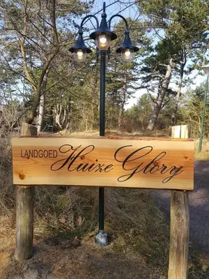 a street light with a sign in a park at Landgoed Huize Glory in Bergen aan Zee