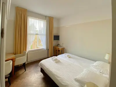 a bedroom with a bed and a desk and a window at Landgoed Huize Glory in Bergen aan Zee