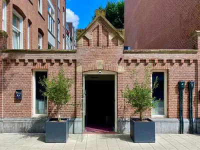 a brick building with a door and two trees in pots at Hotel Van Gogh in Amsterdam