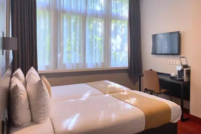 a hotel room with a bed and a desk and a television at Hotel Van Gogh in Amsterdam