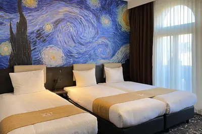 two beds in a room with a painting on the wall at Hotel Van Gogh in Amsterdam