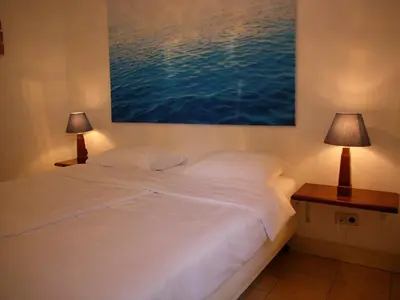 a bedroom with a large white bed with two lamps at Dar Cho Apartment in Zandvoort
