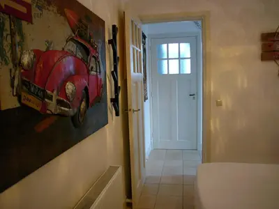 a bathroom with a painting of a red car on the wall at Dar Cho Apartment in Zandvoort