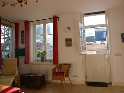 a living room with two windows and a chair at Dar Cho Apartment in Zandvoort