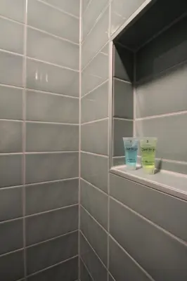 a tiled bathroom with two cups on a shelf at Het Spoorhuis Uithoorn in Uithoorn