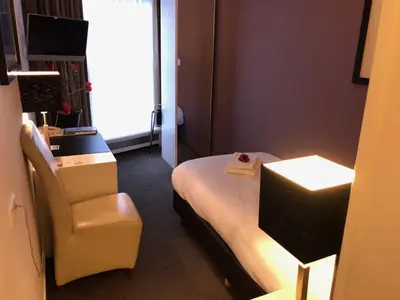 a hotel room with a bed and a chair at Hotel de Keizerskroon Hoorn in Hoorn