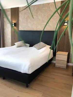 a bedroom with a bed with white sheets and a plant at Hotel de Keizerskroon Hoorn in Hoorn