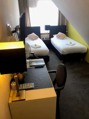 a room with two beds and a desk with a computer at Hotel de Keizerskroon Hoorn in Hoorn